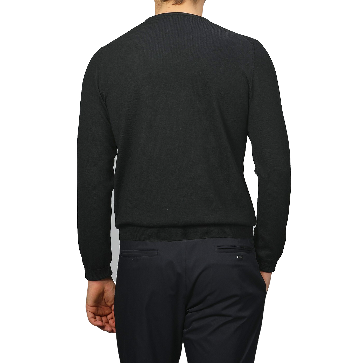 A person is seen from behind, dressed in Gran Sasso's Black Extra Fine Merino Crew Neck and black pants, standing out against a neutral background with classic allure and understated elegance.