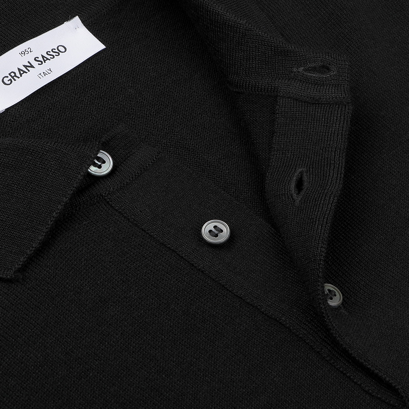 Close-up of the Black Extra Fine Merino Wool Polo Shirt by Gran Sasso, showcasing its three-button design and label detail on the collar.