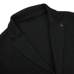 The Black Linen Cotton Knitted Blazer by Gran Sasso showcases a visible metal pin on the lapel, with a close-up of the collar and slim fit upper chest area, set against a white background.