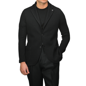 Person in a slim fit Gran Sasso Black Linen Cotton Knitted Blazer over a sleek black shirt, hands casually in pockets, standing against a plain background.