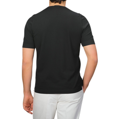 A person is seen from the back wearing Gran Sasso's Black Organic Cotton T-Shirt and white pants, standing against a gray background.