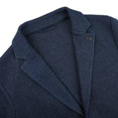 The Gran Sasso Blue Melange Linen Cotton Knitted Blazer, featuring a ribbed texture and lapel pin on the collar, is displayed on a flat white surface.