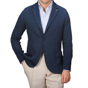 A person wearing a Gran Sasso Blue Melange Linen Cotton Knitted Blazer over a light blue striped shirt with beige pants stands against a plain gray background.