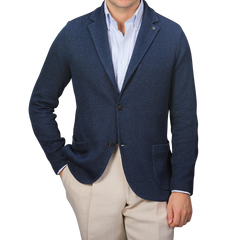 A person wearing a Gran Sasso Blue Melange Linen Cotton Knitted Blazer over a light blue striped shirt with beige pants stands against a plain gray background.