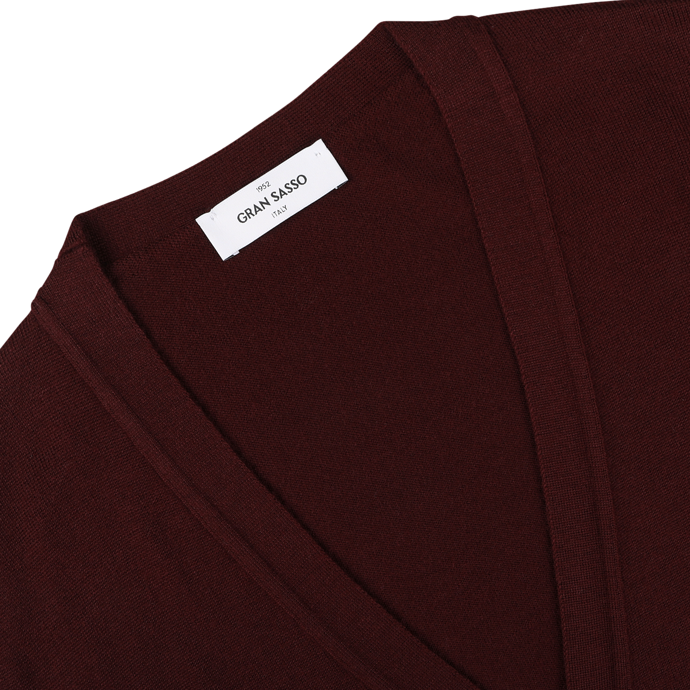 A close-up of the Bordeaux Extra Fine Merino Wool Cardigan reveals its exquisite detail: a maroon V-neck sweater with a white label that reads "Gran Sasso Italy.