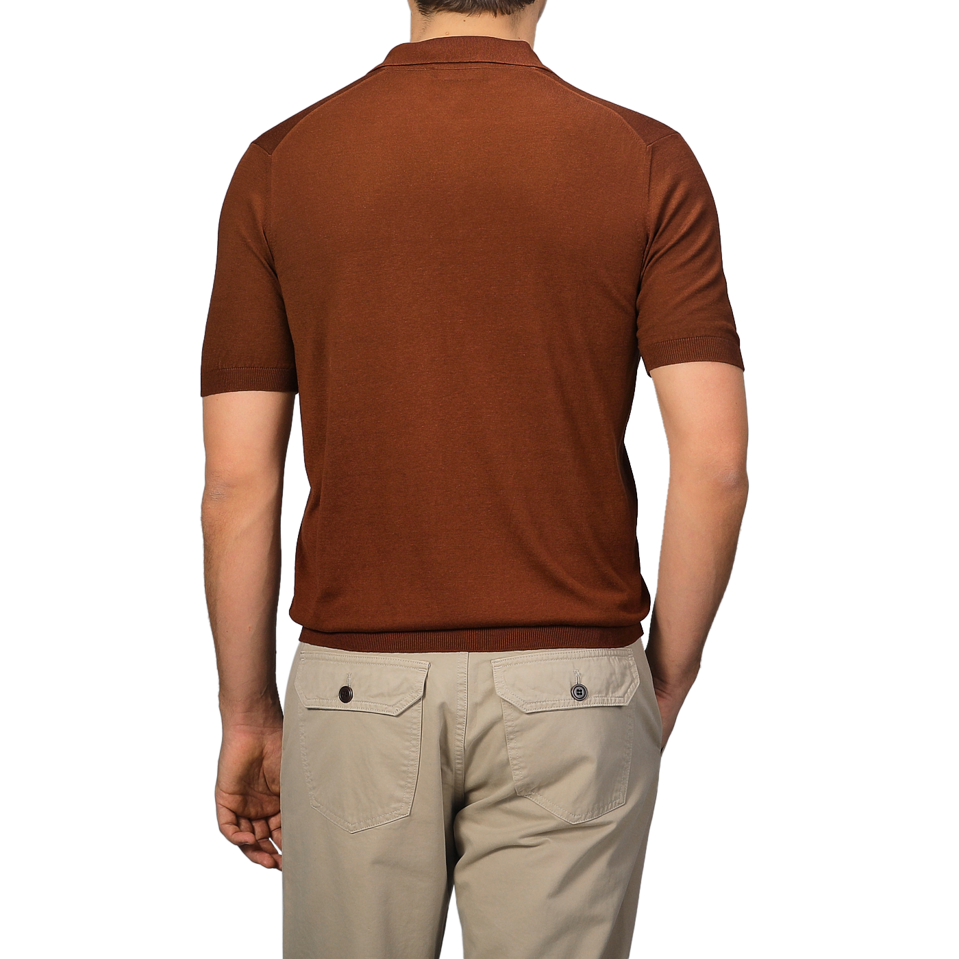 A man wearing a Brick Red Knitted Silk Polo Shirt by Gran Sasso and beige pants stands with his back to the camera, showcasing the essence of a refined summer wardrobe.