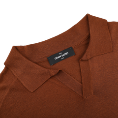 This brick red knitted silk polo shirt, a stylish touch for any summer wardrobe, boasts a visible black label with "Gran Sasso" elegantly displayed inside.