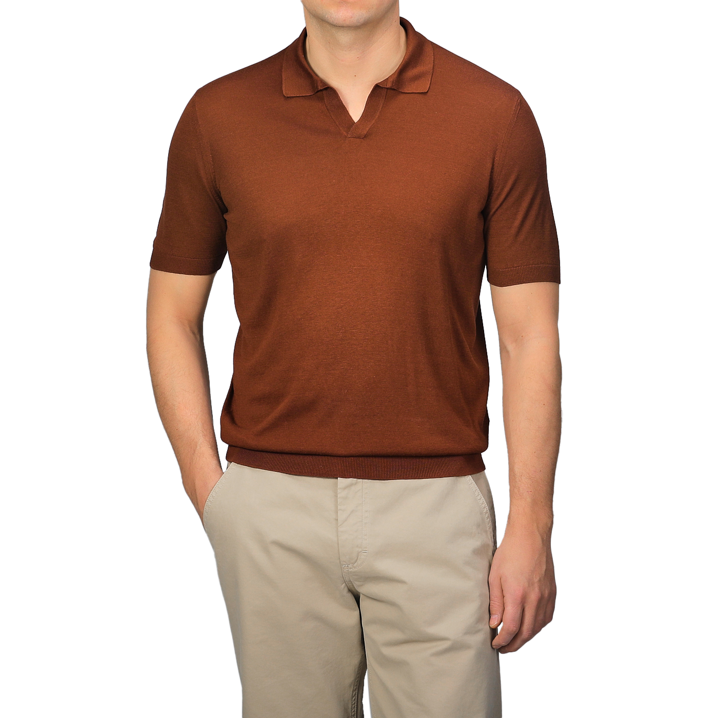 A person wearing a Brick Red Knitted Silk Polo Shirt by Gran Sasso and beige pants stands with one hand in their pocket against a neutral background, showcasing a refined summer wardrobe.