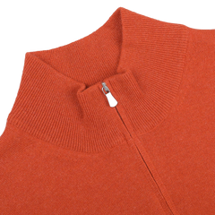 Close-up of a Bright Orange Cashmere 1/4 Zip Sweater by Gran Sasso, featuring a ribbed collar, lying flat against a neutral background.