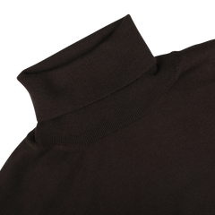 Close-up of a Brown Extra Fine Merino Roll Neck from Gran Sasso laid flat, showcasing its folded neck and the fine texture of the thin wool fabric.