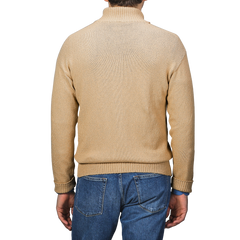 A man in a Gran Sasso Camel Beige Cotton Boucle Full Zip Cardigan and blue jeans stands with his back to us, exuding classic style.