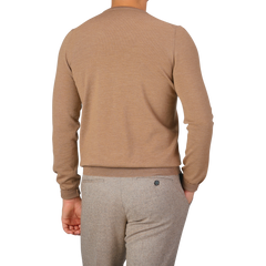 Rear view of a person wearing a Gran Sasso Camel Beige Extra Fine Merino Crew Neck and gray pants, standing against a plain background.