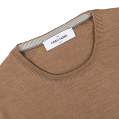 Close-up of a Camel Beige Extra Fine Merino Crew Neck sweater made by Gran Sasso, featuring a white tag inside the crew neck collar that says "Gran Sasso Italy.