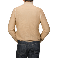 A person wearing a Gran Sasso Camel Beige Vintage Wool Zip Cardigan pairs it with dark jeans, standing with their back to the camera against a gray background.