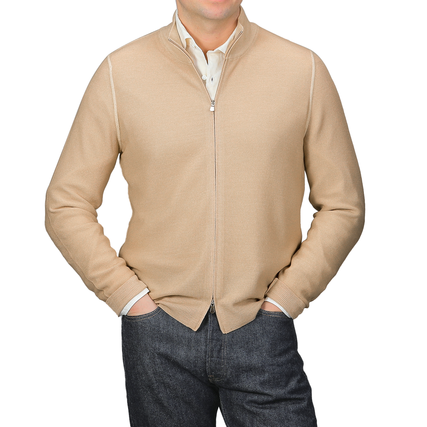 A person in a Gran Sasso Camel Beige Vintage Wool Zip Cardigan over a white collared shirt and dark jeans stands against a gray background, hands in pockets.