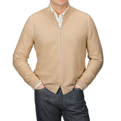 A person in a Gran Sasso Camel Beige Vintage Wool Zip Cardigan over a white collared shirt and dark jeans stands against a gray background, hands in pockets.