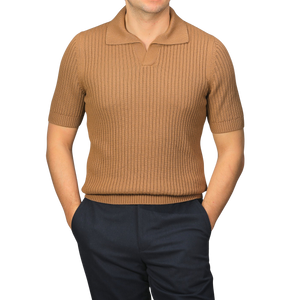 A person wearing a slim-fit Camel Brown Organic Cotton Polo Shirt by Gran Sasso and dark pants stands with hands in pockets against a plain background.