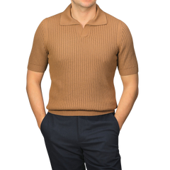 A person wearing a slim-fit Camel Brown Organic Cotton Polo Shirt by Gran Sasso and dark pants stands with hands in pockets against a plain background.