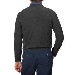 A person is shown from the back against a plain background, wearing a Charcoal Grey Cashmere V-Neck Sweater by Gran Sasso and dark blue pants, both meticulously crafted from pure cashmere fibers.