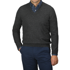 A person wearing Gran Sasso's Charcoal Grey Cashmere V-Neck Sweater over a denim shirt, paired with dark blue pants, stands against a neutral background.