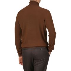 Rear view of a person wearing a slim fit Cinnamon Brown Extra Fine Merino Rollneck and dark brown trousers from Gran Sasso.