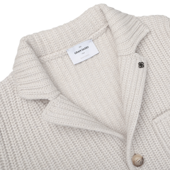 Close-up of a Cream Beige Chunky Knitted Wool Cardigan by Gran Sasso, featuring a folded collar, a label reading "Gran Sasso," and a buttoned pocket.