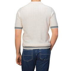 A person wearing a Gran Sasso Cream Beige Cotton Linen T-Shirt featuring dark sleeve and hem stripes, paired with slim fit blue jeans, viewed from the back.