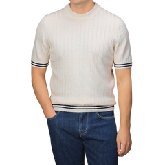 A person in a Gran Sasso slim fit light-colored Cream Beige Cotton Linen T-Shirt with black trim and blue jeans, hands in pockets.