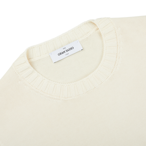 A close up of a Gran Sasso cream beige Egyptian cotton crewneck sweater with a label on it.