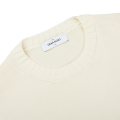 A close up of a Gran Sasso cream beige Egyptian cotton crewneck sweater with a label on it.