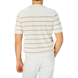 Man standing with his back to the camera wearing a Gran Sasso Cream Beige Striped Organic Cotton T-Shirt and white pants.