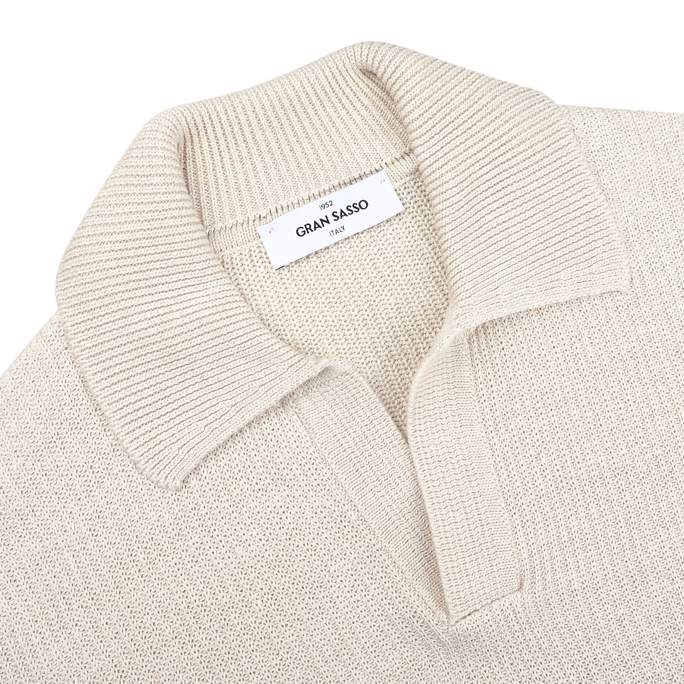 A slim-fit cream polo shirt, made from cotton-linen thread, lies flat with a label displaying "Gran Sasso Italy.