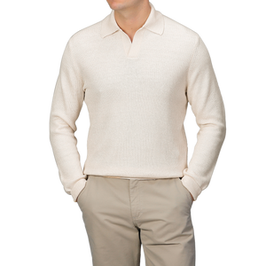 A person wears a slim fit Cream Cotton Linen LS Polo Shirt by Gran Sasso, paired with beige pants, hands casually tucked in pockets against a gray backdrop.