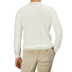 A person wearing a Cream Extra Fine Merino Crew Neck by Gran Sasso and beige corduroy pants, viewed from the back against a plain black background, exemplifies the versatility of a multi-purpose wardrobe.