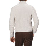 A person wearing a cream Pure Cashmere Quarter Button Sweater from Gran Sasso and brown pants is shown from the back against a plain background.