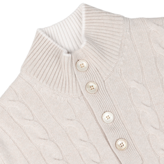 Close-up of a cream pure cashmere quarter button sweater featuring a cable-knit design, high ribbed collar, and three vertically aligned beige buttons in the front. Crafted with impeccable care, this Gran Sasso creation exudes timeless elegance.