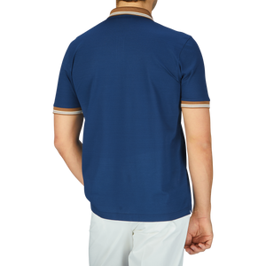 The high-quality Dark Blue Filo Scozia zip polo shirt by Gran Sasso worn by the man is paired with white pants, as seen from the back.