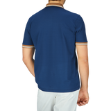 The high-quality Dark Blue Filo Scozia zip polo shirt by Gran Sasso worn by the man is paired with white pants, as seen from the back.