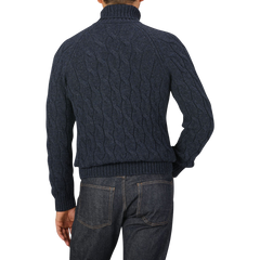 A person is wearing a Gran Sasso Dark Blue Wool Cable Knit Rollneck sweater and dark blue jeans. The photo is taken from the back, showcasing the sweater's texture and design.