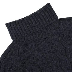 Close-up of Gran Sasso's Dark Blue Wool Cable Knit Rollneck sweater, highlighting its chunky texture and ribbed collar, made from pure virgin wool against a plain background.