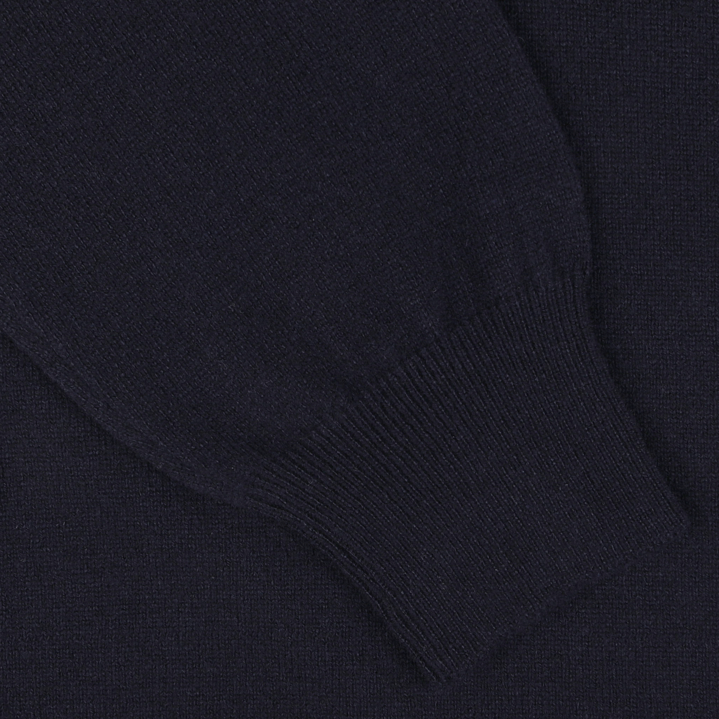 Close-up of a Gran Sasso Dark Blue Wool Cashmere 1/4 Zip Sweater sleeve with a ribbed cuff, against a matching fabric background.