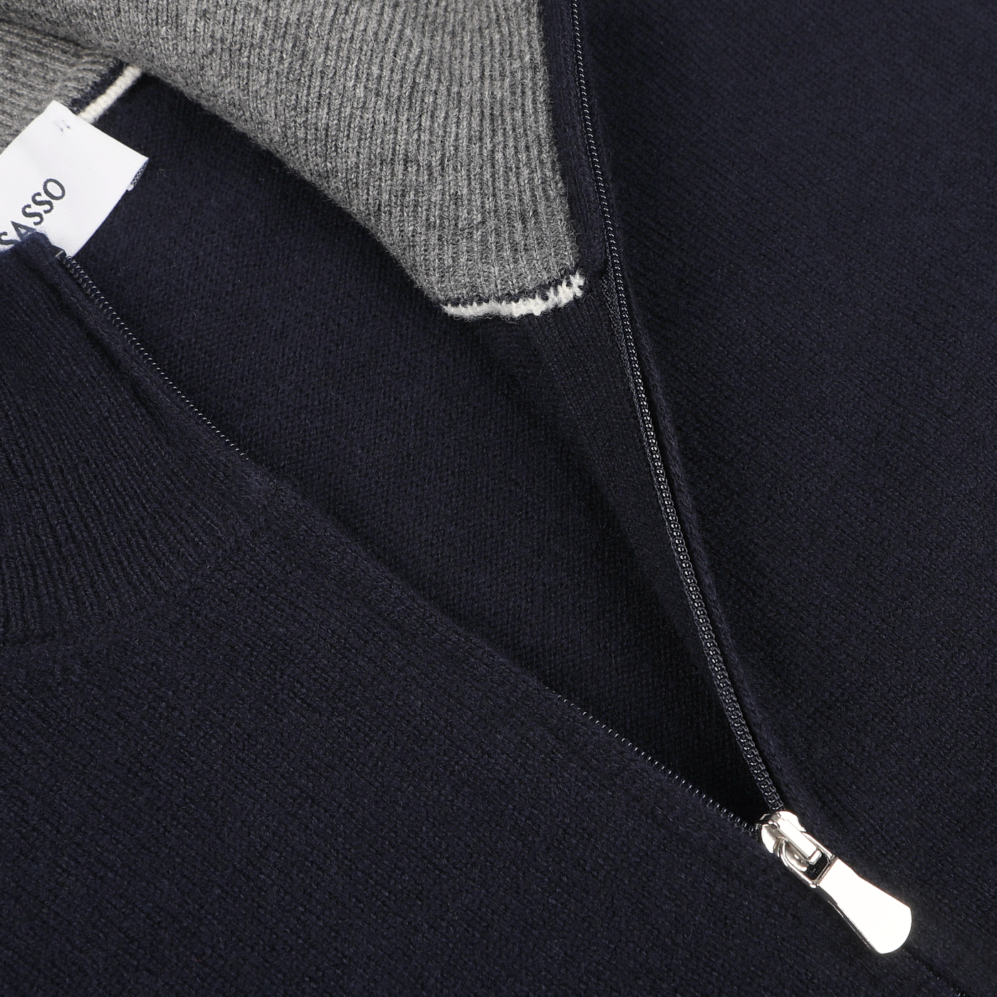 Close-up of a Dark Blue Wool Cashmere 1/4 Zip Sweater by Gran Sasso, featuring a silver zipper, revealing a gray inner lining and a partially visible clothing tag on the left side.