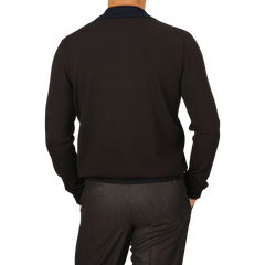 A person wearing a Dark Brown Extra Fine Merino LS Polo Shirt from Gran Sasso and gray pants is shown from the back with their hands in their pockets.