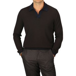 A man is standing with his hands in his pockets, wearing a dark brown long-sleeve collared sweater crafted from extra-fine merino wool by Gran Sasso and dark pants against a light gray background. His face is not visible.