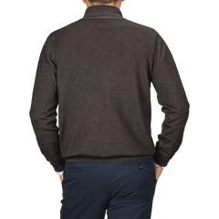 Rear view of a person wearing a Gran Sasso Dark Brown Vintage Merino Zip Cardigan and dark blue pants, with one hand in their pocket.