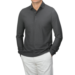 Wearing a Gran Sasso Dark Grey Washed Cotton Popover Shirt with white pants, an individual stands against a neutral background. The slim fit of the pure cotton jersey accentuates their silhouette as they casually rest their hands in their pockets.