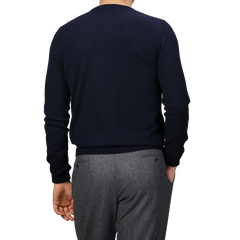 A person wears a Dark Navy Cashmere Crewneck Sweater by Gran Sasso, paired with gray pants, and is shown from the back.