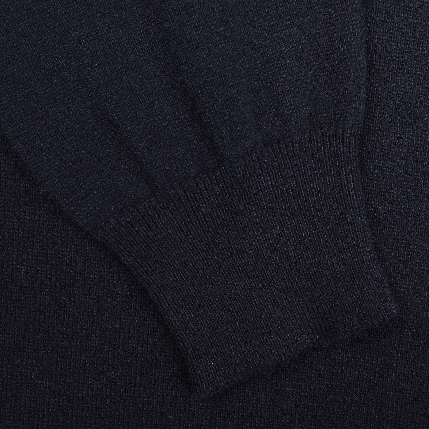 Close-up of a dark knitted fabric, featuring the ribbed cuff of the Dark Navy Cashmere Crewneck Sweater by Gran Sasso. The texture is smooth with visible stitching, highlighting the elegance of pure cashmere in sustainable knitwear.