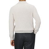 A person facing away, wearing a Gran Sasso Ecru Beige Chunky Knit Wool Polo Shirt made of super Geelong wool and dark trousers. The background is plain and neutral.