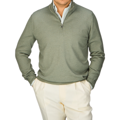 A man wearing a Gran Sasso Grass Green Vintage Merino Wool 1/4 Zip Sweater and white pants, exuding a vintage feel.